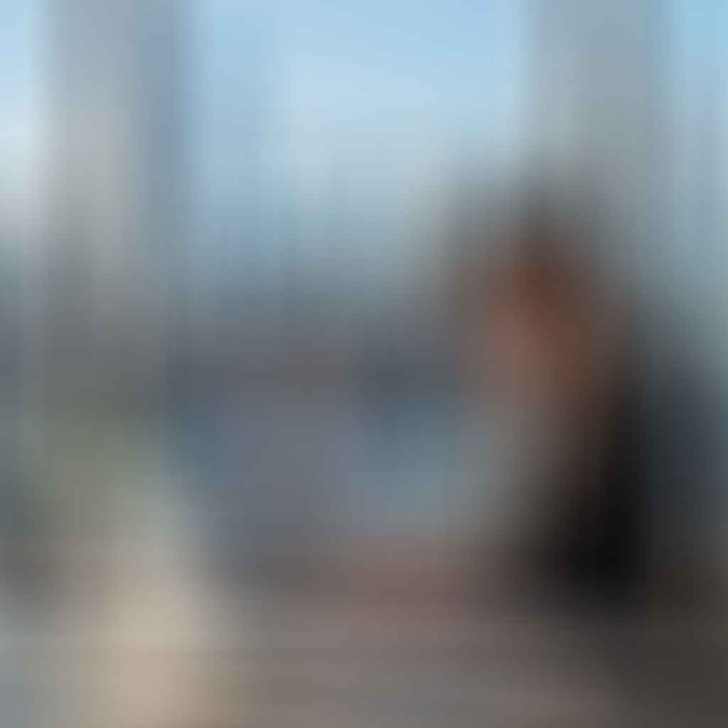 A business professional working at a desk with a laptop and documents, explaining what is title insurance with the New York City skyline visible through a window behind them.
