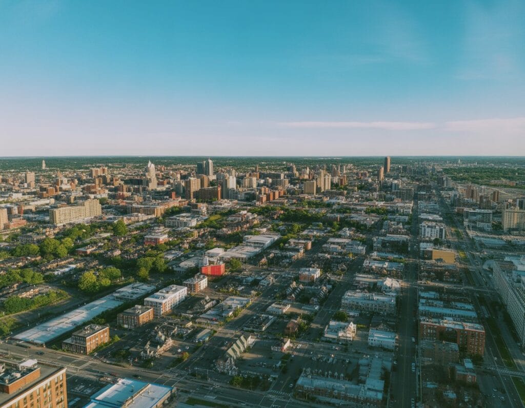 A detailed aerial view of Newark city showing various neighborhoods, buildings, streets, and parks under clear daylight.